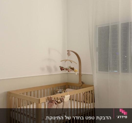 חדר ילדים עם מיטת תינוק וילון לבן